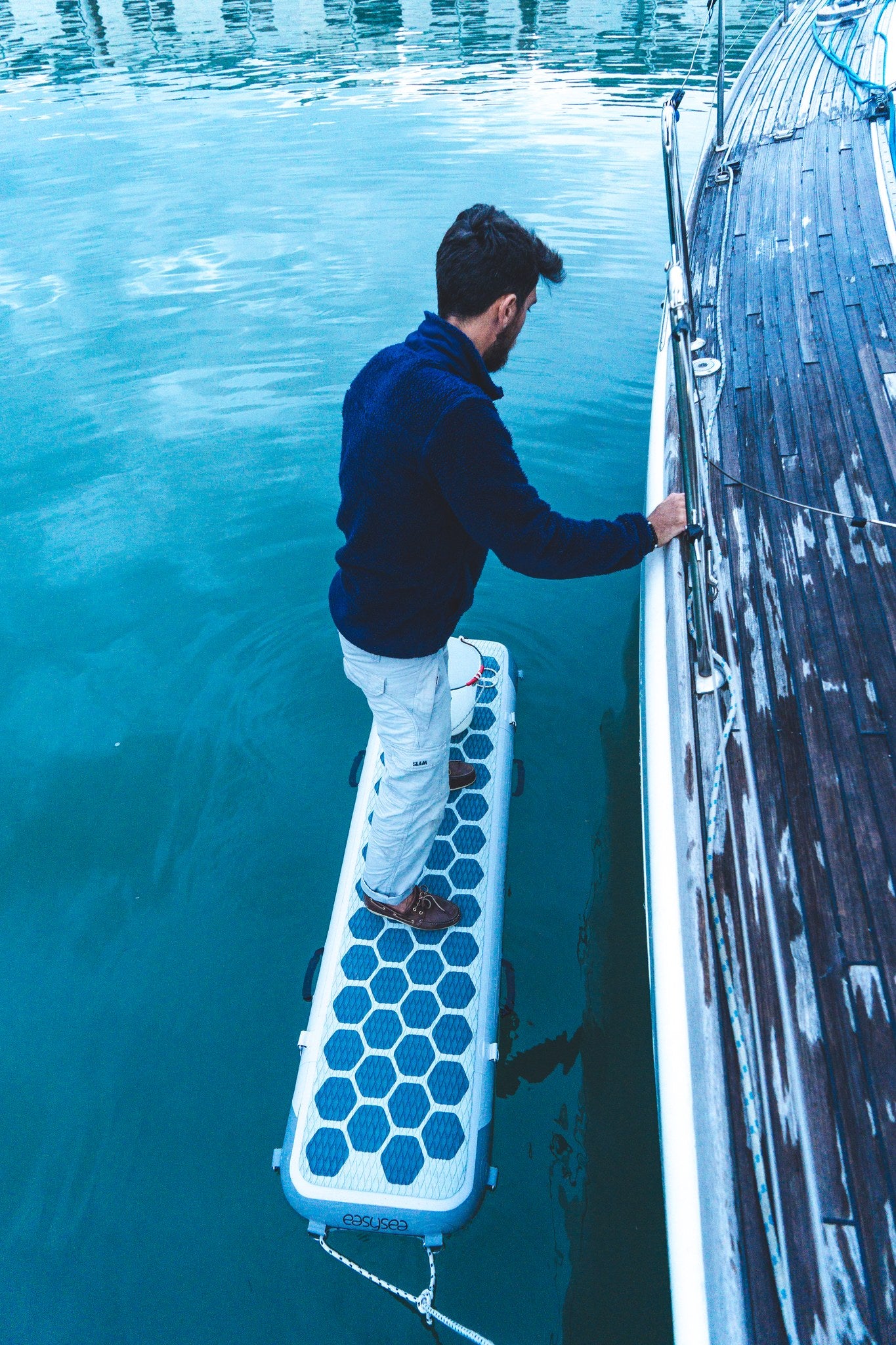 Person standing on the easysea WAY2 inflatable gangway between the dock and a sailing yacht